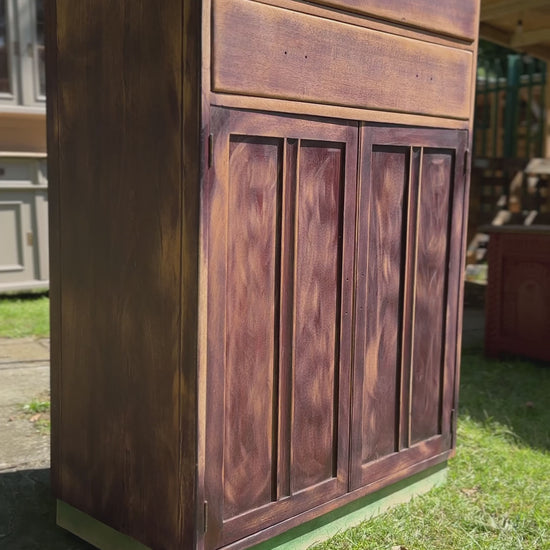 vintage retro mid century tallboy cupboard being painted in small and co sussex brick, an orange peach toned terracotta red colour, hand painted in the UK by UK made paints